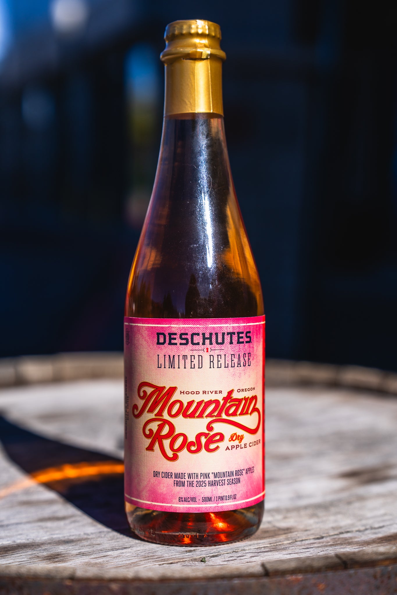 Bottle of Deschutes Mountain Rose Apple Cider on a wooden surface with a blurred background
