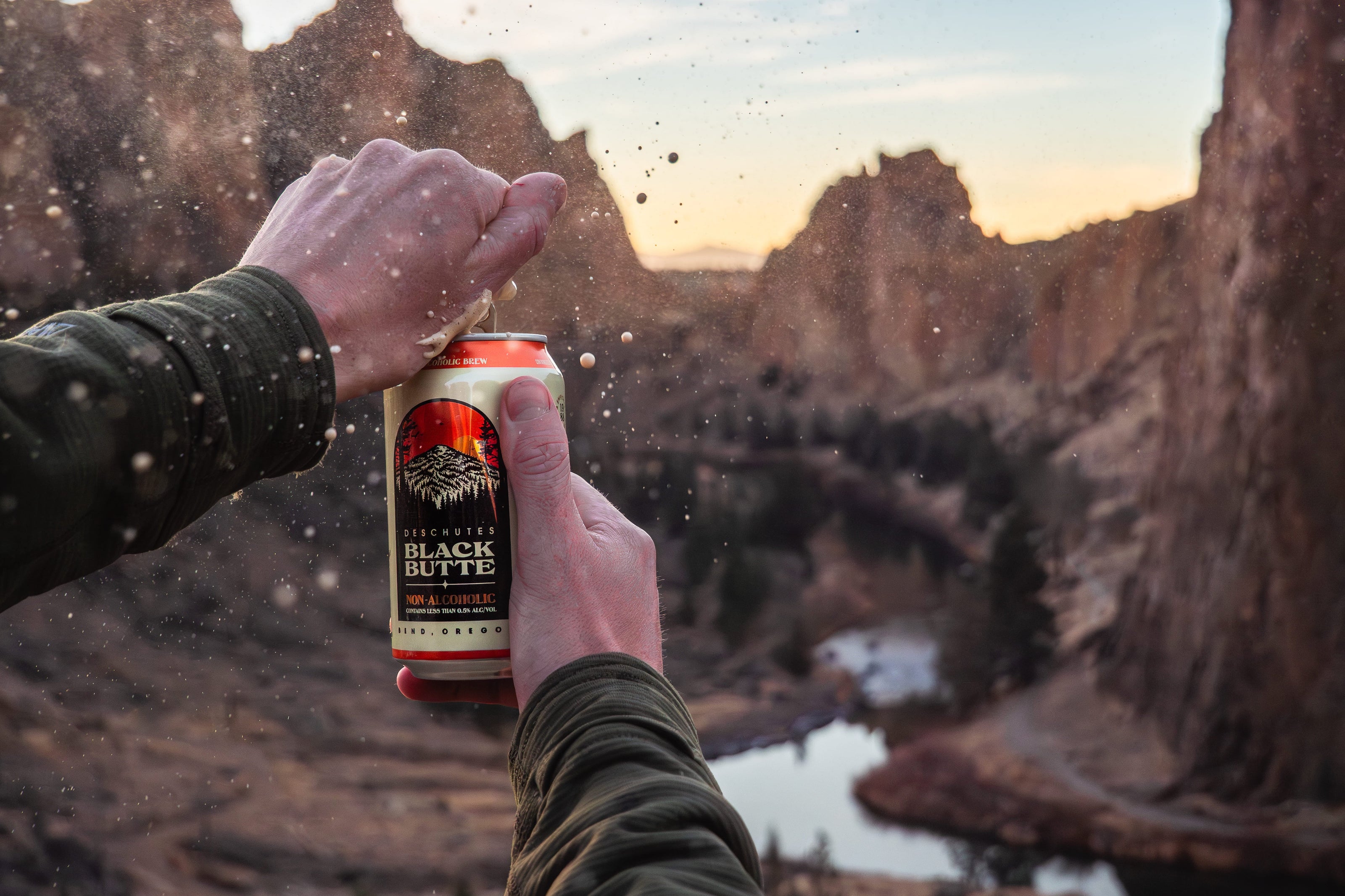 Person holding a can of Black Butte Non-Alcoholic beer with a scenic background